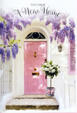 This Kilburn entrance captures the gentle thrill of a new home, framed by a lovingly crafted floral scene. The front door is painted in a delicate shade of pink, subtle yet inviting, and it sits within a whitewashed wall whose slightly uneven texture catches the changing light. Cascading from above and along the sides, wisteria blooms in cascading sheets of lavender and light purple, their blossoms forming loose, tumbling clusters that soften the doorway's lines. Each strand is made of many tiny petals, creating a soft, cloud-like fringe that feels both romantic and slightly wild, like wisteria you might glimpse climbing over garden walls near Kilburn Grange Park. On the stone step, a grey tin florist's bucket has been transformed into the focal point by an abundant gathering of creamy white and ivory roses. Their petals are thick and velvety, spiralling open with fullness, and they nestle among sprigs of fresh green foliage that spill gently over the rim. Around the base of the bucket, a narrow satin ribbon in soft pink is tied into a simple, elegant bow, its colour echoing the painted door and silently tying the whole composition together. Light filters through the trailing wisteria and nearby leaves, creating a pattern of dappled sunlight and cool shade over the flowers, doorstep, and lower panels of the door. The atmosphere is serene yet full of expectancy, the kind of moment that might greet someone arriving with housewarming wishes from West Hampstead or Maida Vale. Every element - from the pastel tones to the lush roses - feels like a tender message of congratulations, welcome, and the enduring hope that this new address will quickly become a place of comfort and belonging.